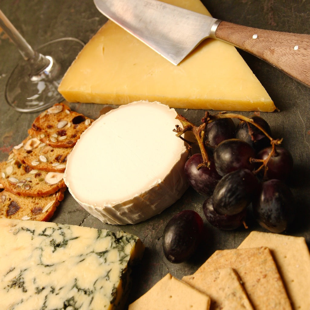 Pieces of cheese on cheese board with crackers and cheese knife