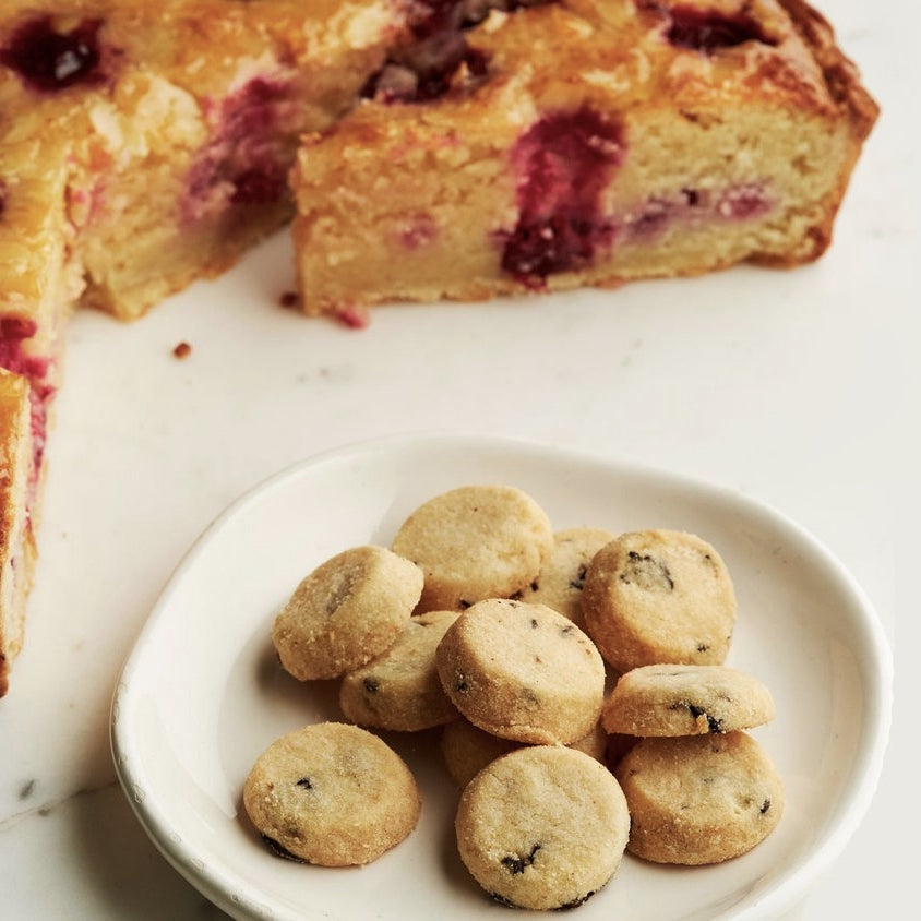Cherry & almond biscuits on a plate with a Bakewell Tart in the background