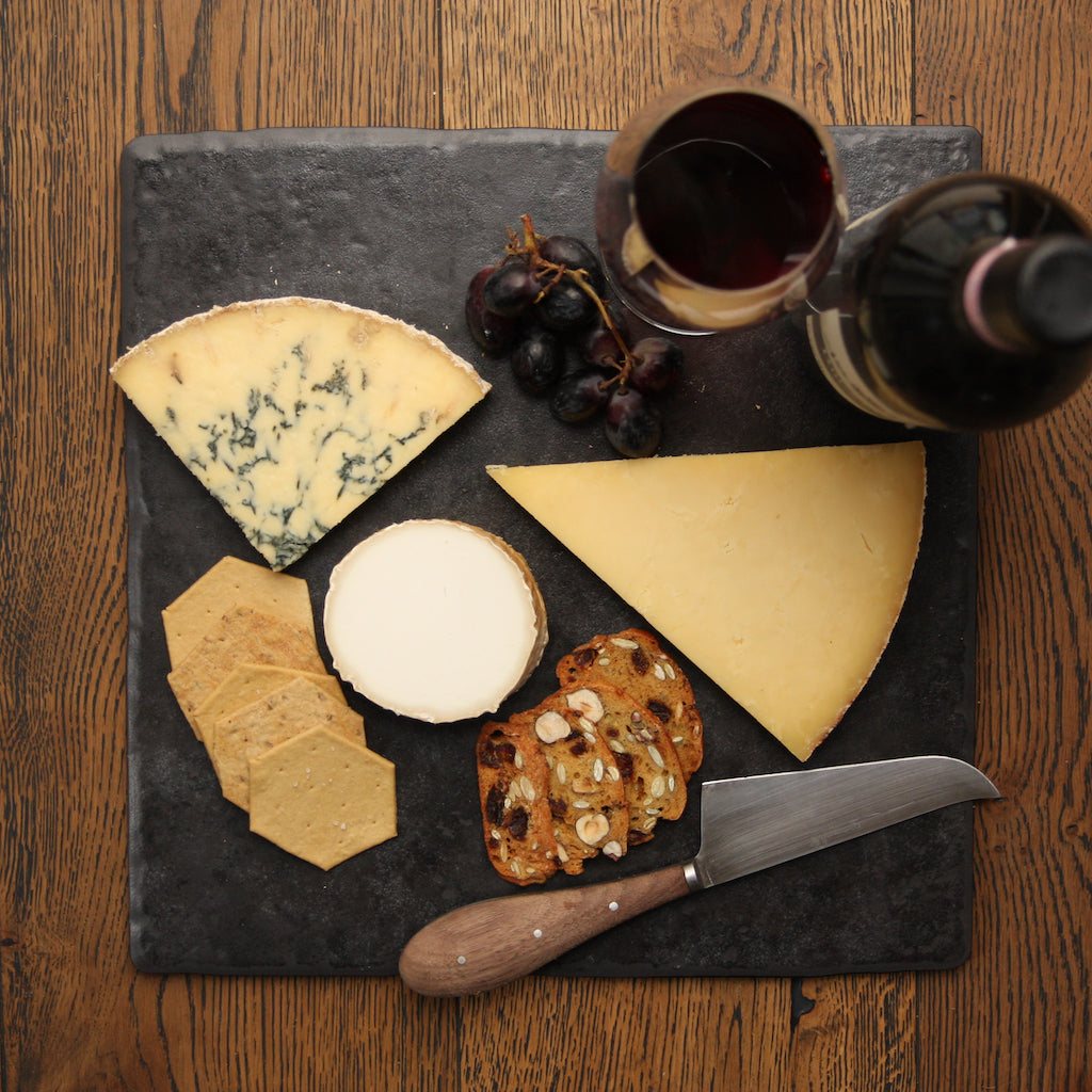 Smoked Stilton on slate with other smoked cheeses, crackers, wine and grapes