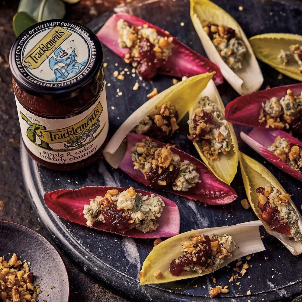 Tracklements apple & cider chutney with endive leaves filled with Stilton & Nuts on a slate surface.