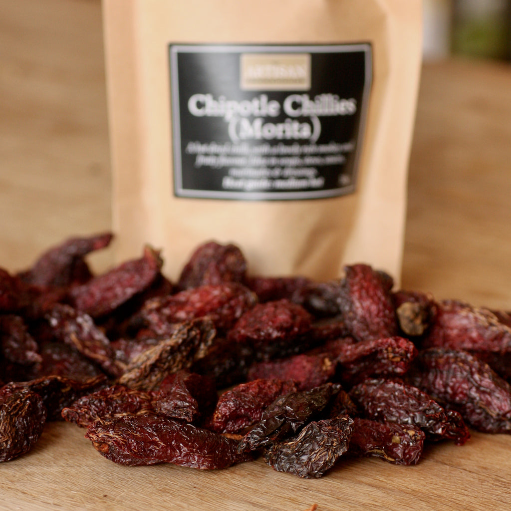 Bag of chipotle chilis with dried chilis on a wooden surface
