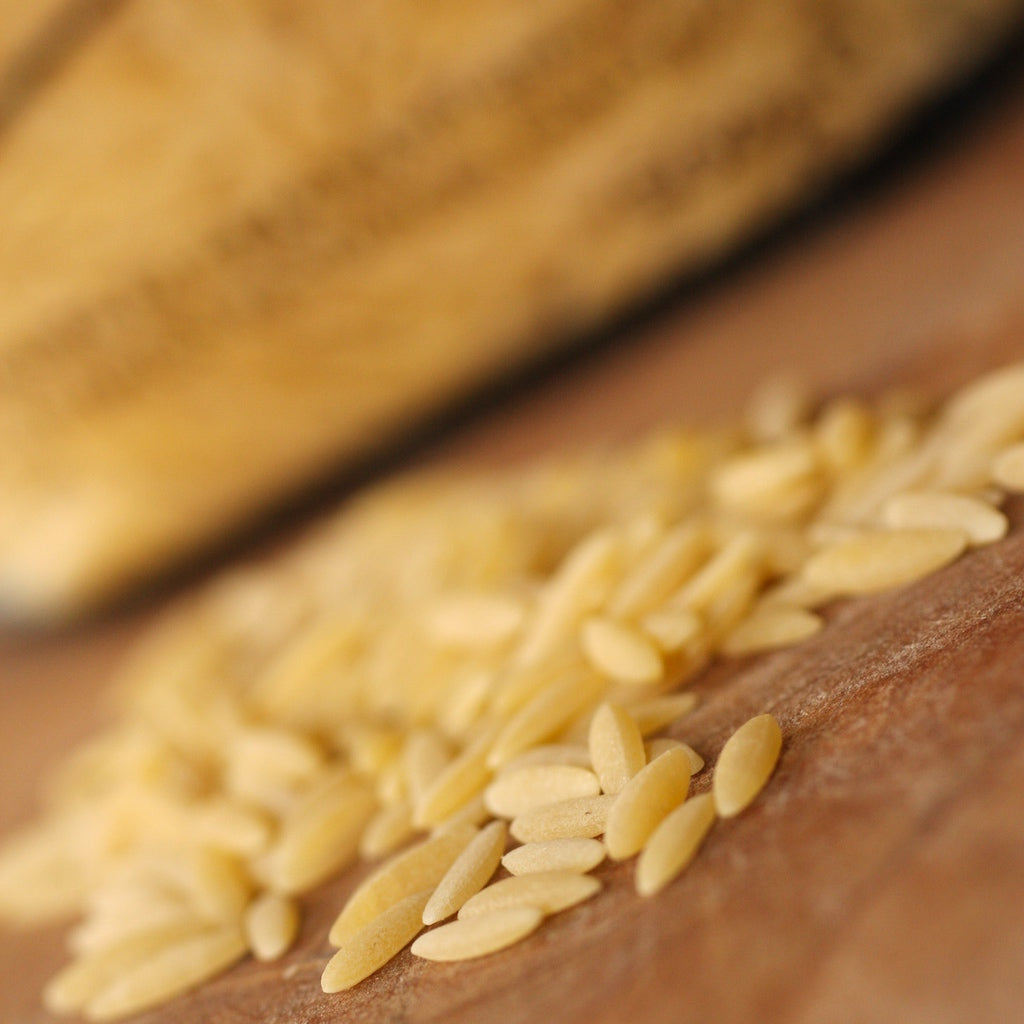Close-up of uncooked orzo pasta on a wooden surface