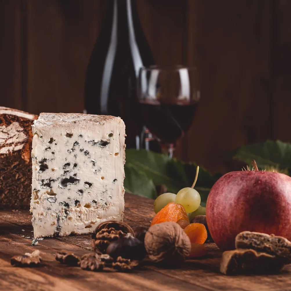 A piece of Fourme d'Ambert on cheese board with red wine