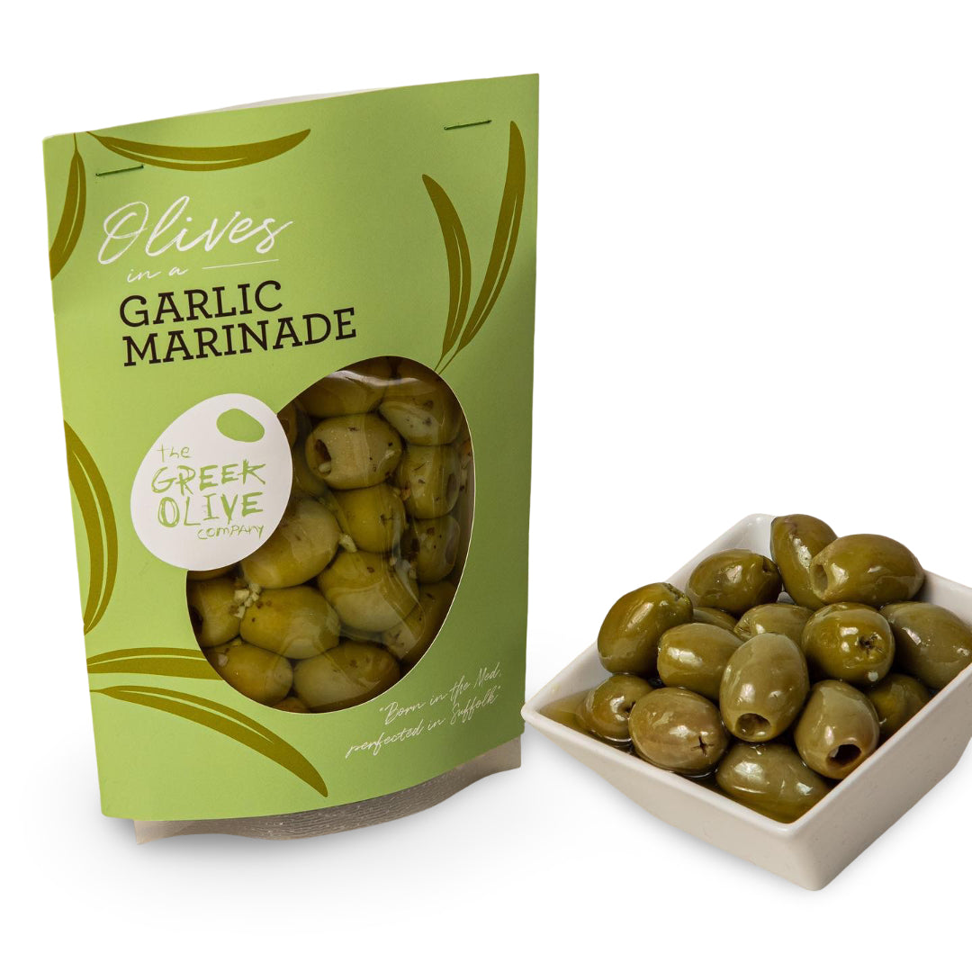 Green package of Garlic Marinade olives next to a bowl of olives on a white background