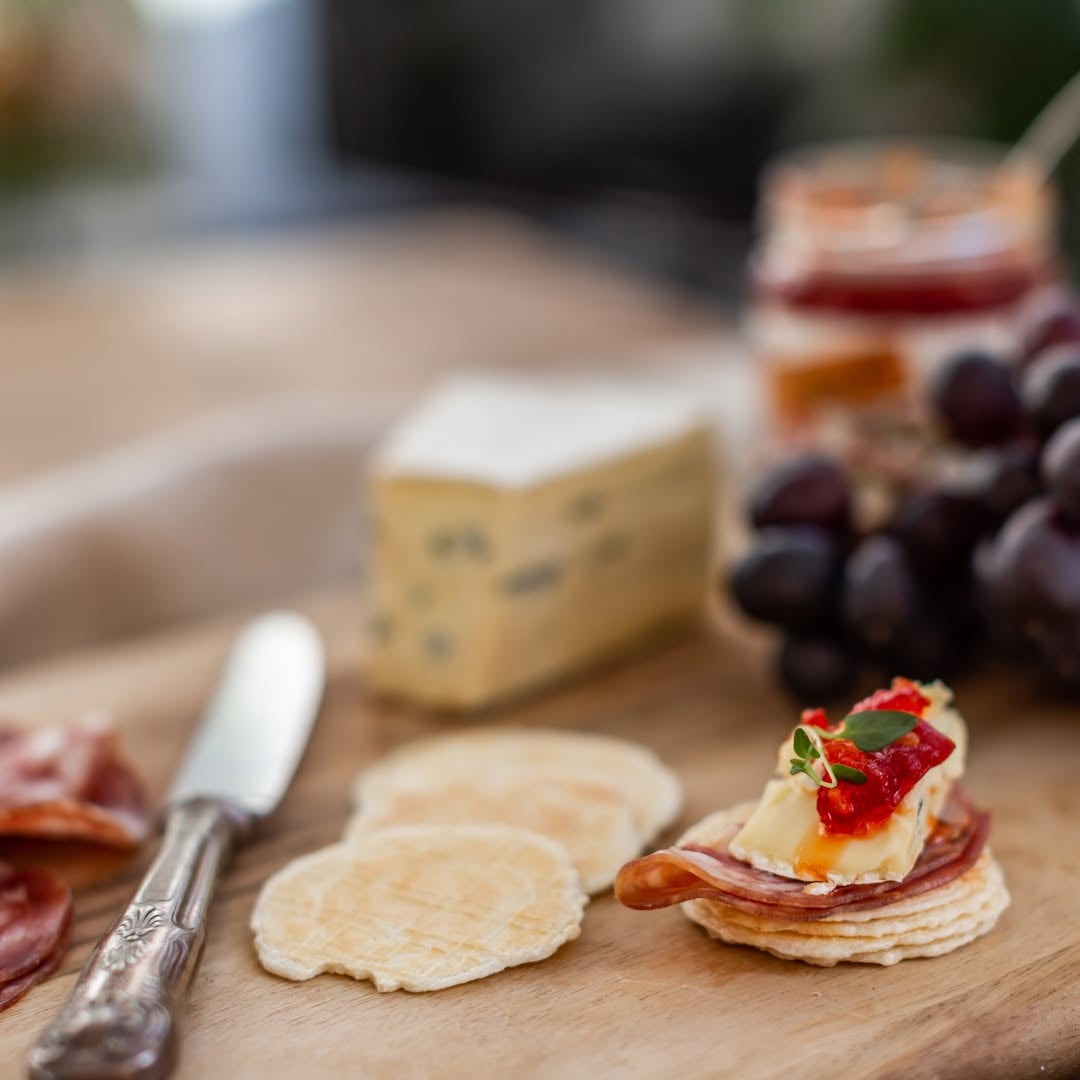 Wooden board with gluten free crackers, prosciutto, cheese, and grapes