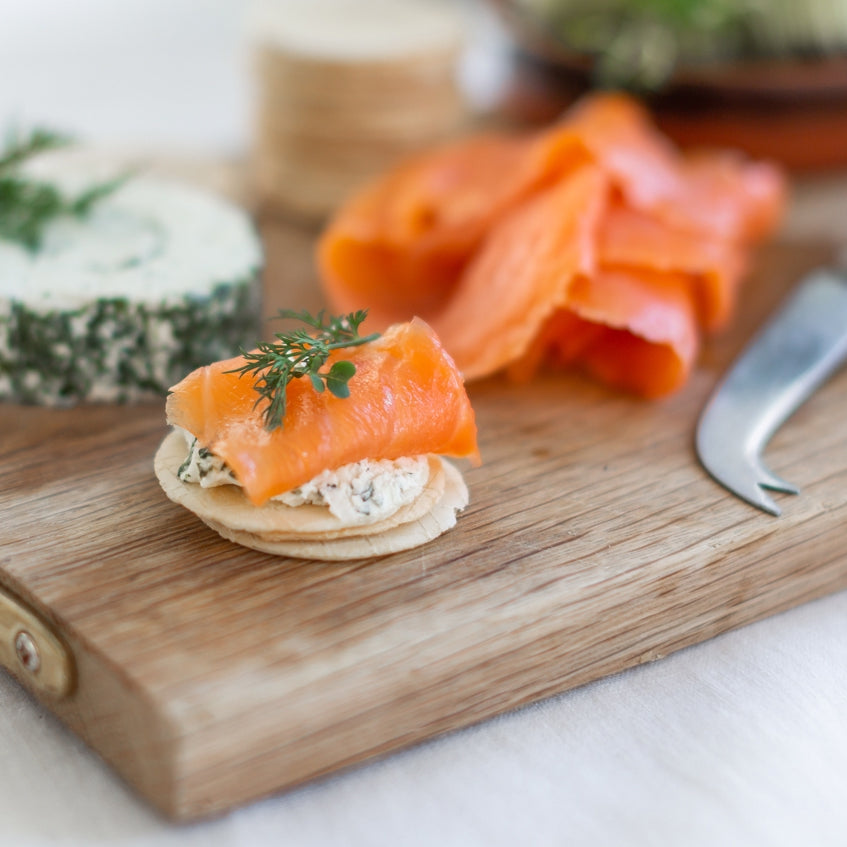 Smoked salmon and cream cheese canapés on gluten free crackers, on a wooden board