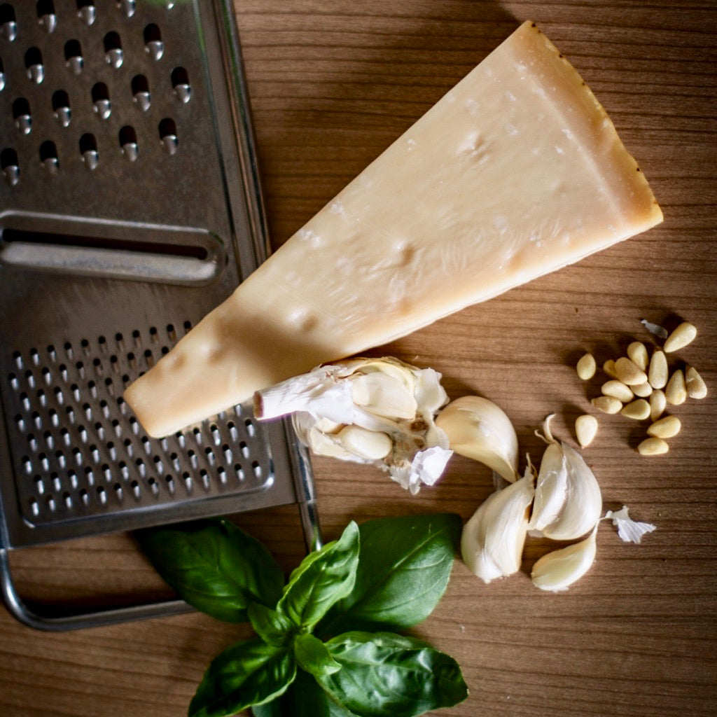 A chunk of aged Parmesan on board with basil and pine nuts