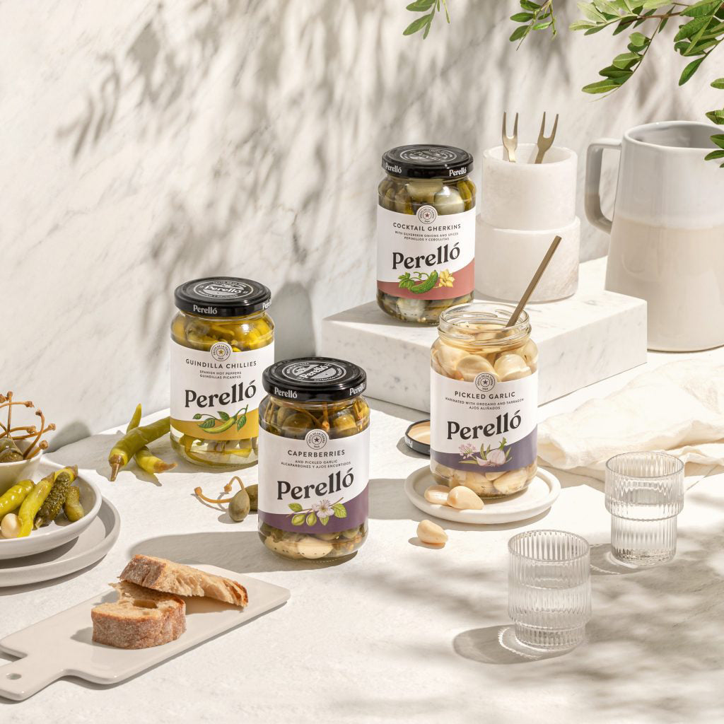 Perello jarred pickles on a table with bread and glasses