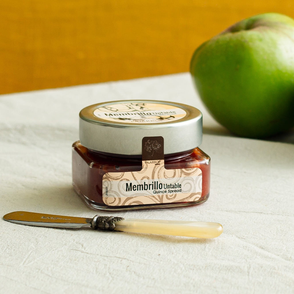 A jar of Membrillo quince jam with knife and quince