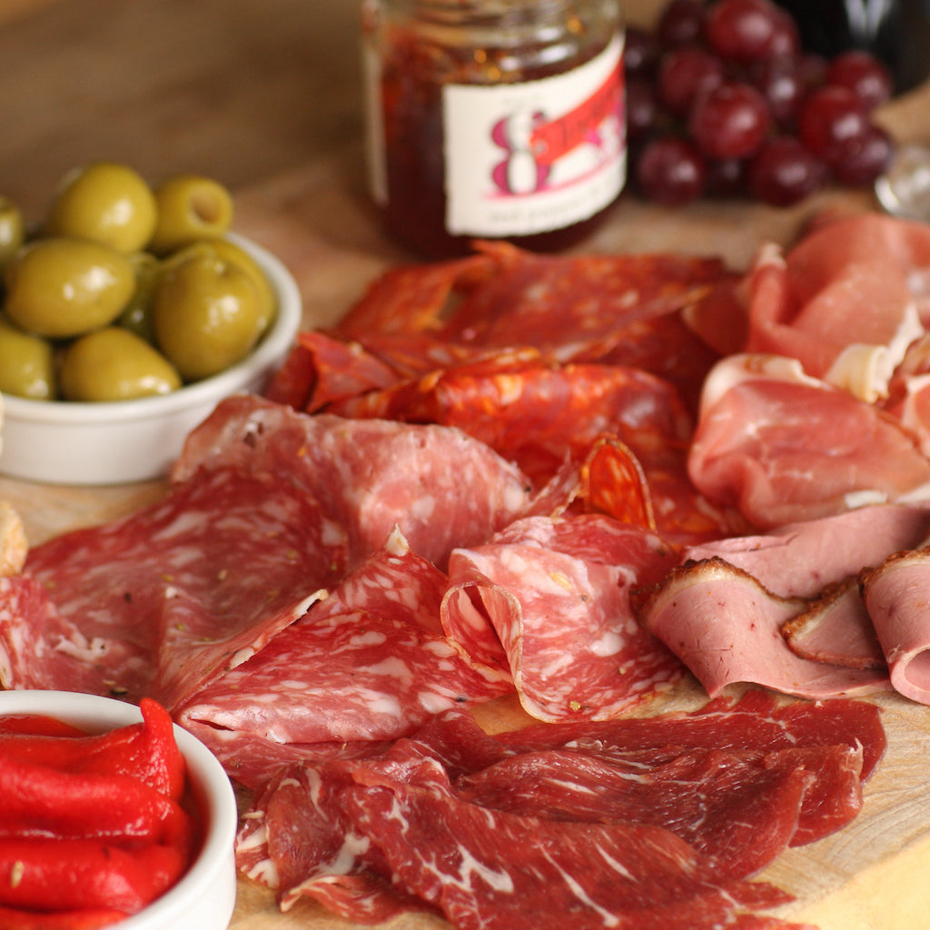 Slices of The Artisan Smokehouse's smoked beef fillet on meat platter with smoked olives and roasted peppers