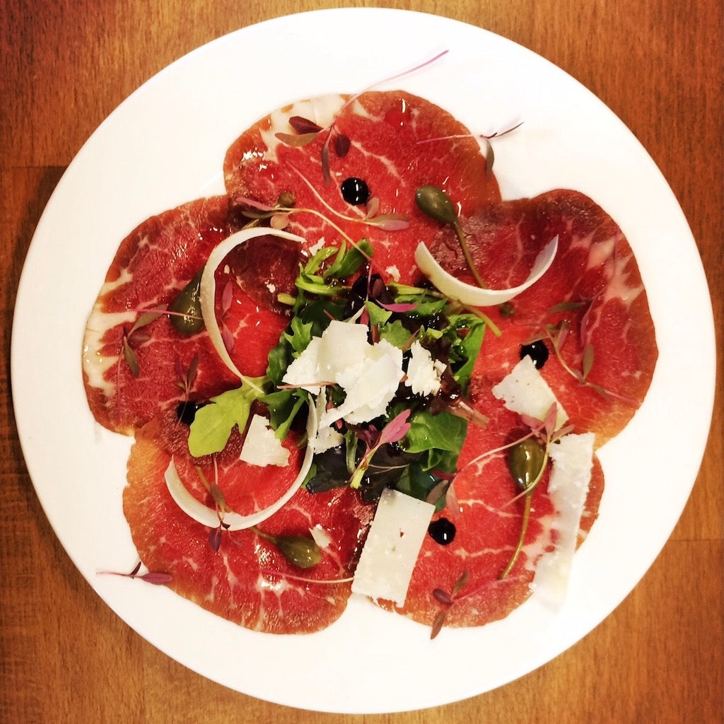 Artisan Smokehouse smoked beef fillet carpaccio on plate served with rocket, Parmesan and capers