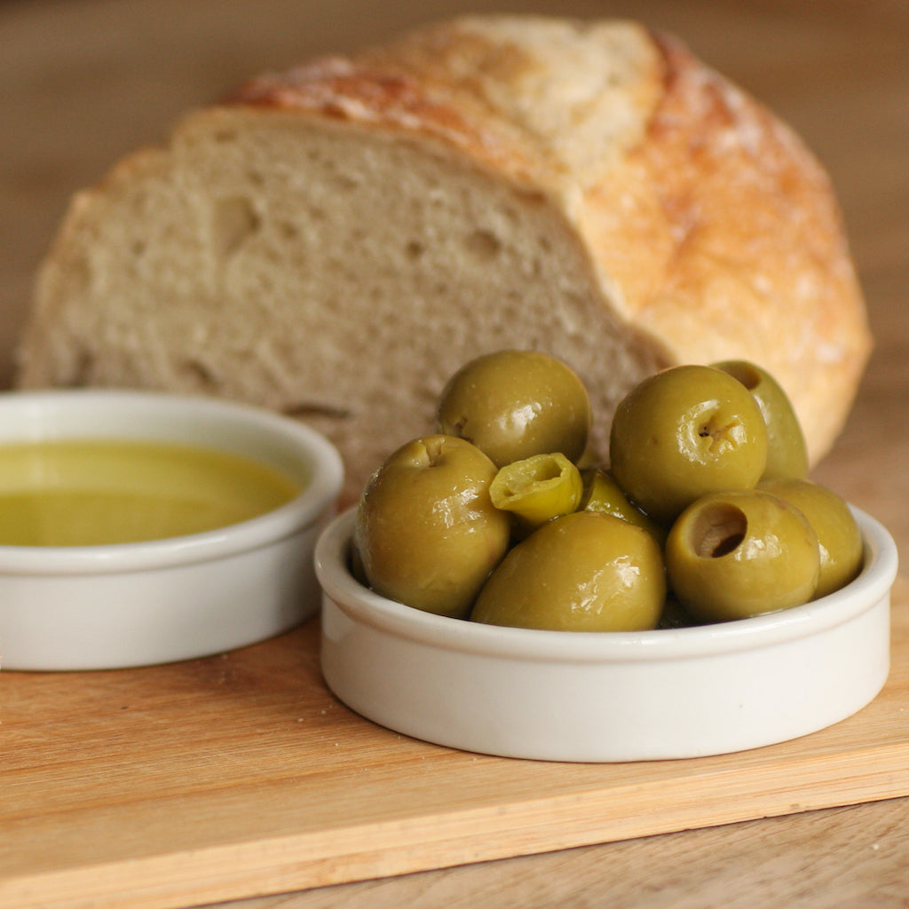 A bowl of The Artisan Smokehouse's maple smoked olives and olive oil on board with bread