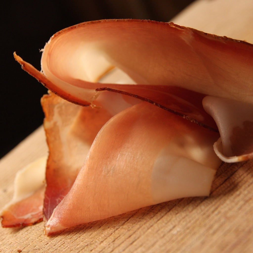 Sliced smoked Prosciutto ham on wooden board