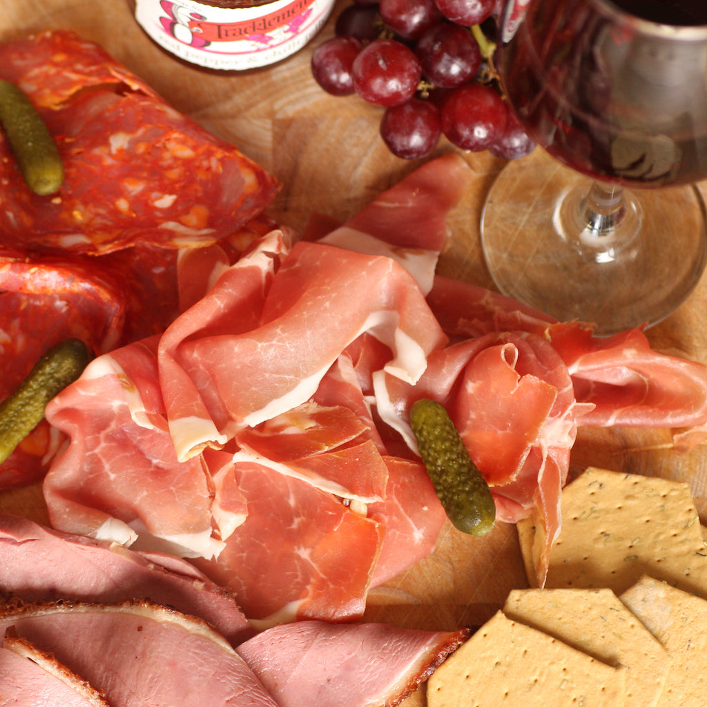 Slices of The Artisan Smokehouse's smoked Prosciutto ham on meat platter with grapes and wine