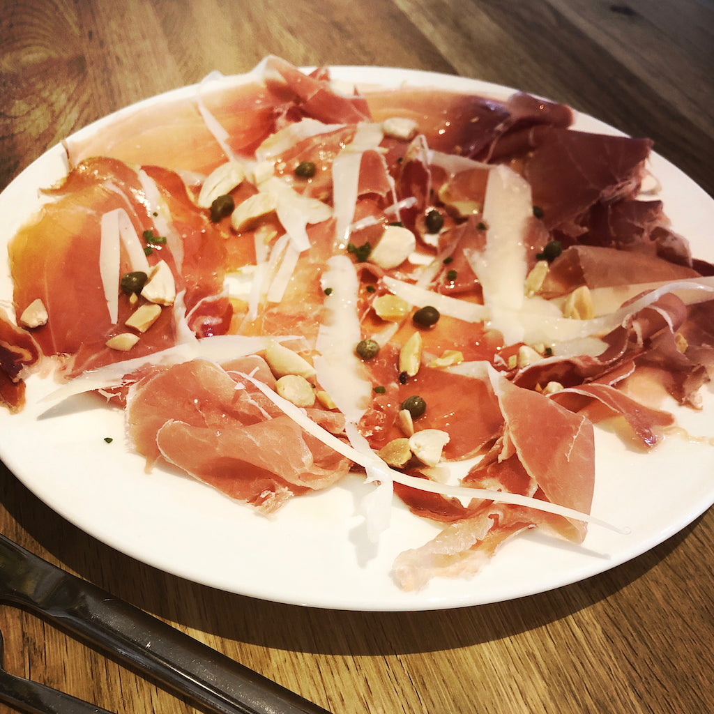 A plate of The ArtisanSmokehouse's smoked Prosciutto with Parmesan, almonds and capers