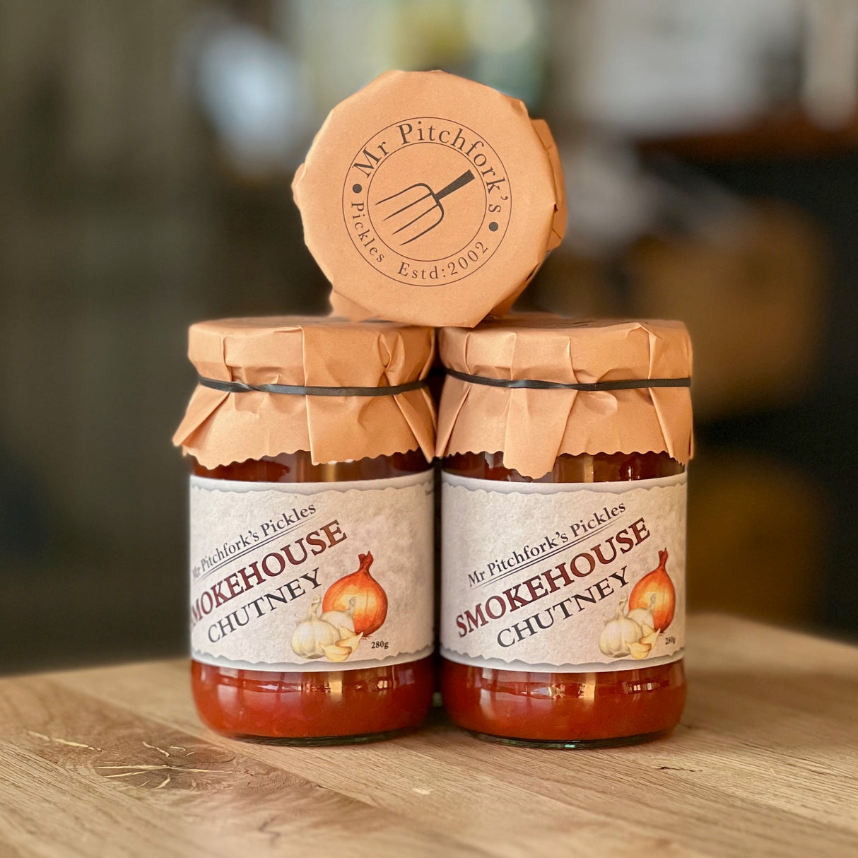 Three jars of Smokehouse Chutney on a wooden surface