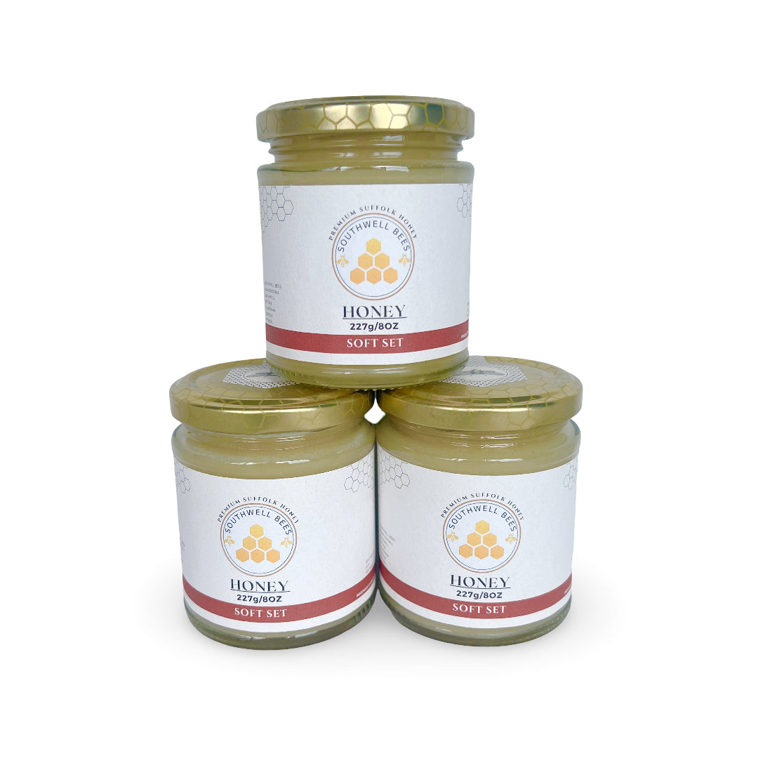 Three jars of soft set honey stacked on a white background with a visible brand label.
