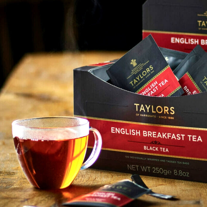Taylors English Breakfast tea packaging with a cup of tea on a wooden surface