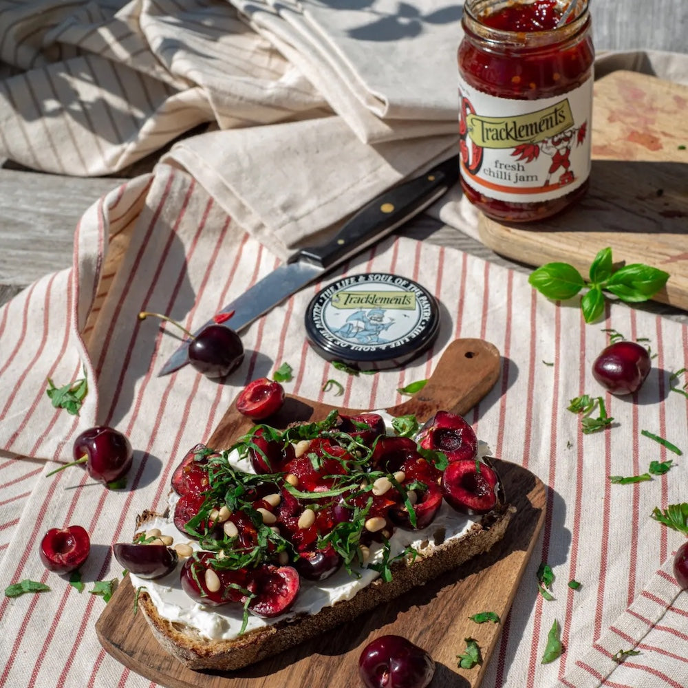 Bruschetta with cherries and herbs on a wooden board with Tracklemens Fresh Chill Jam.
