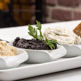 Assorted dips, including black olive paste, in small bowls on a platter