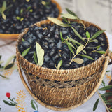 Wicker basket filled with black olives on a floral tablecloth