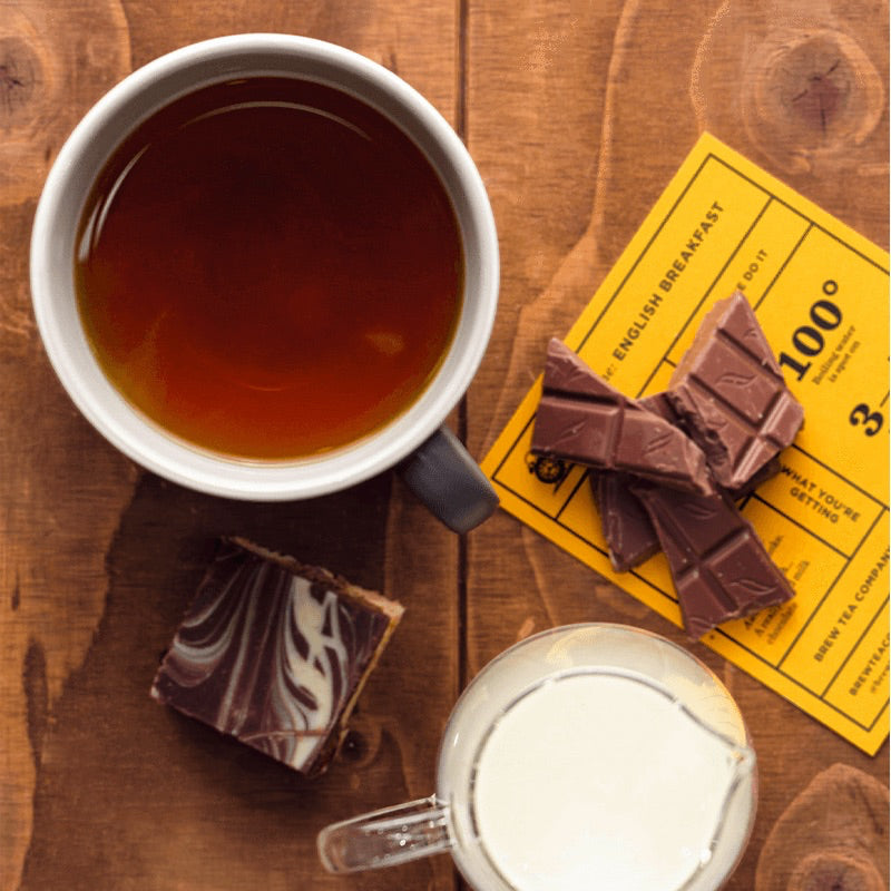 A cup of English Breakfast with chocolate pieces on the side