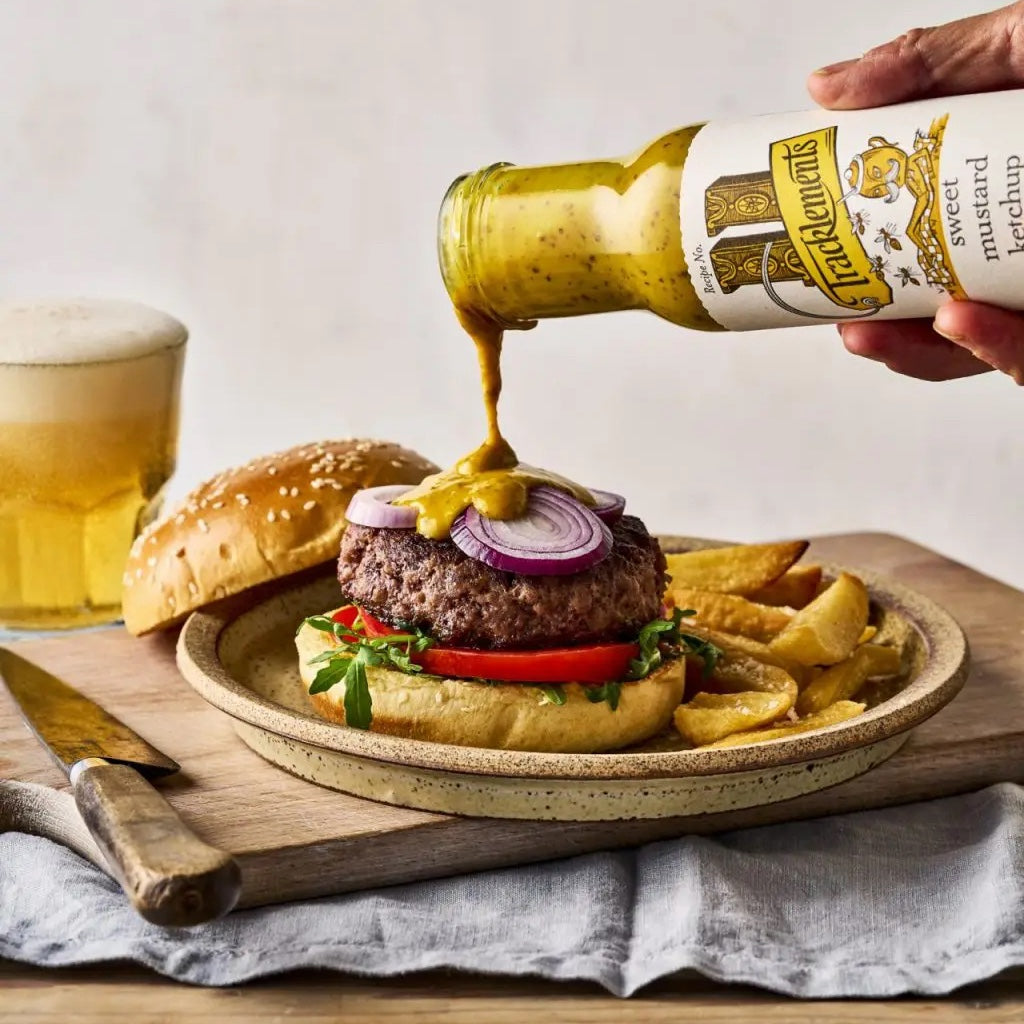 Tracklements Sweet Mustard Ketchup being poured onto a burger