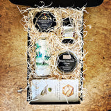 Cheese gift box with Snowdonia cheese, olives, and other items on a wooden surface