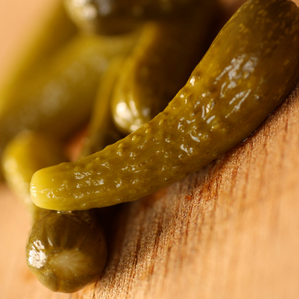 Several cocktail gherkins on serving board