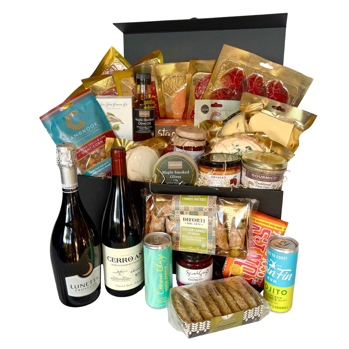 A luxury gourmet gift hamper filled with an assortment of premium food items, including wine, cocktails, charcuterie, crackers, cheeses, and packaged snacks, arranged inside and around an open black gift box on a white background.