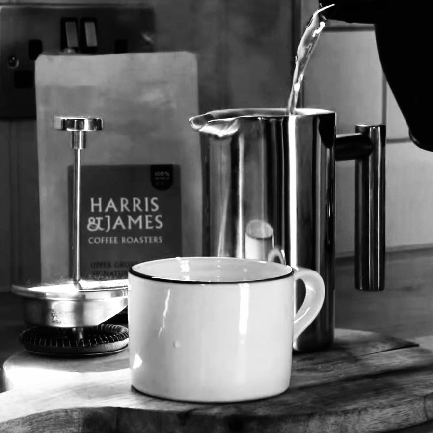 A cup of coffee next to a bag of Harris & James coffee