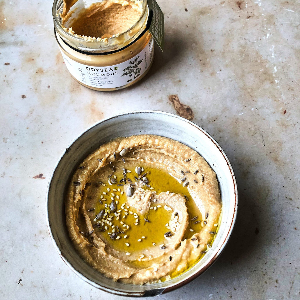 A bowl of houmous with olive oil and seeds