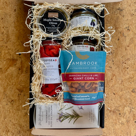 The Meze gift set with assorted food items including jars of meze, peppers, crackers a and giant corn
