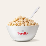 Bowl of Perello pickled garlic cloves with a spoon on a light background