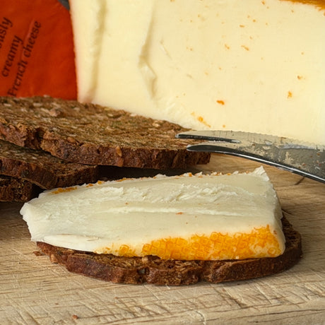 Cracker with slice of Port Salut on a wooden board