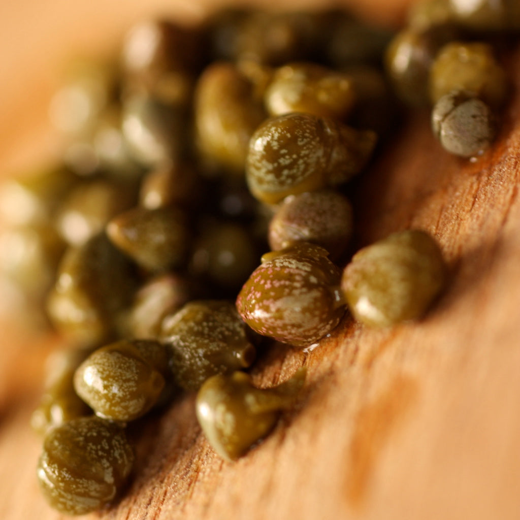 Baby capers on wooden board