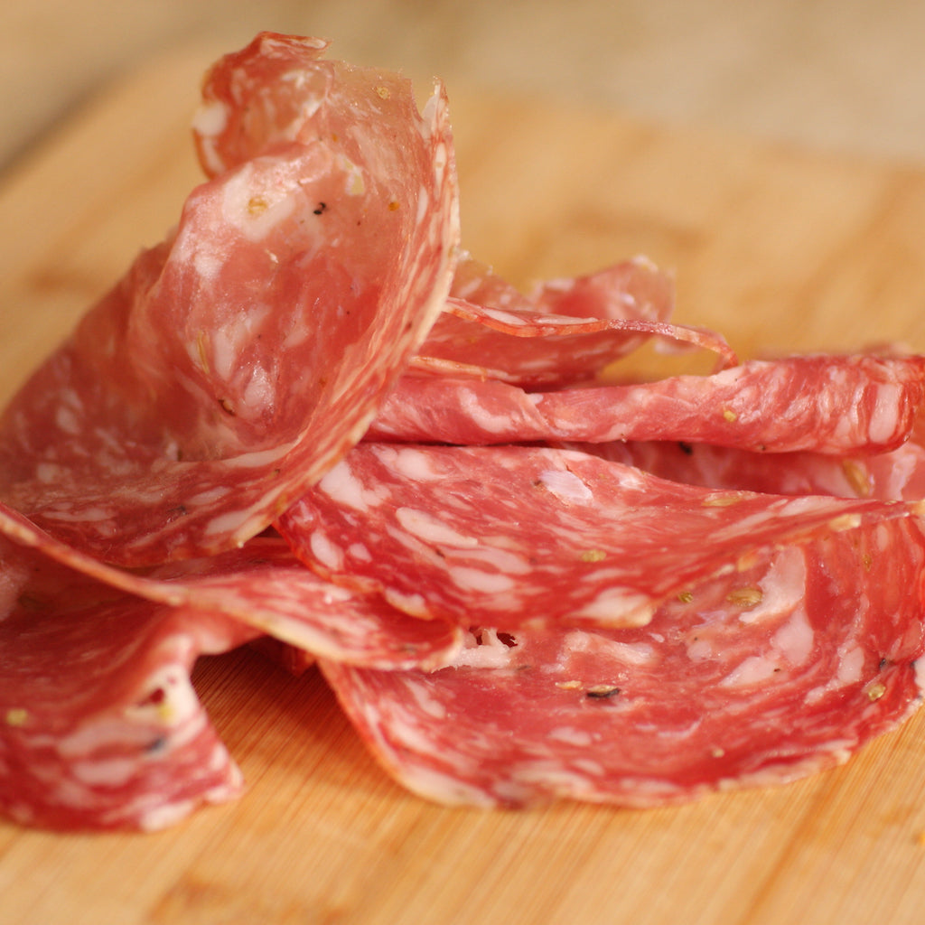 Slices of The Artisan-Smokehouse's smoked Finocchiona salami on wooden board