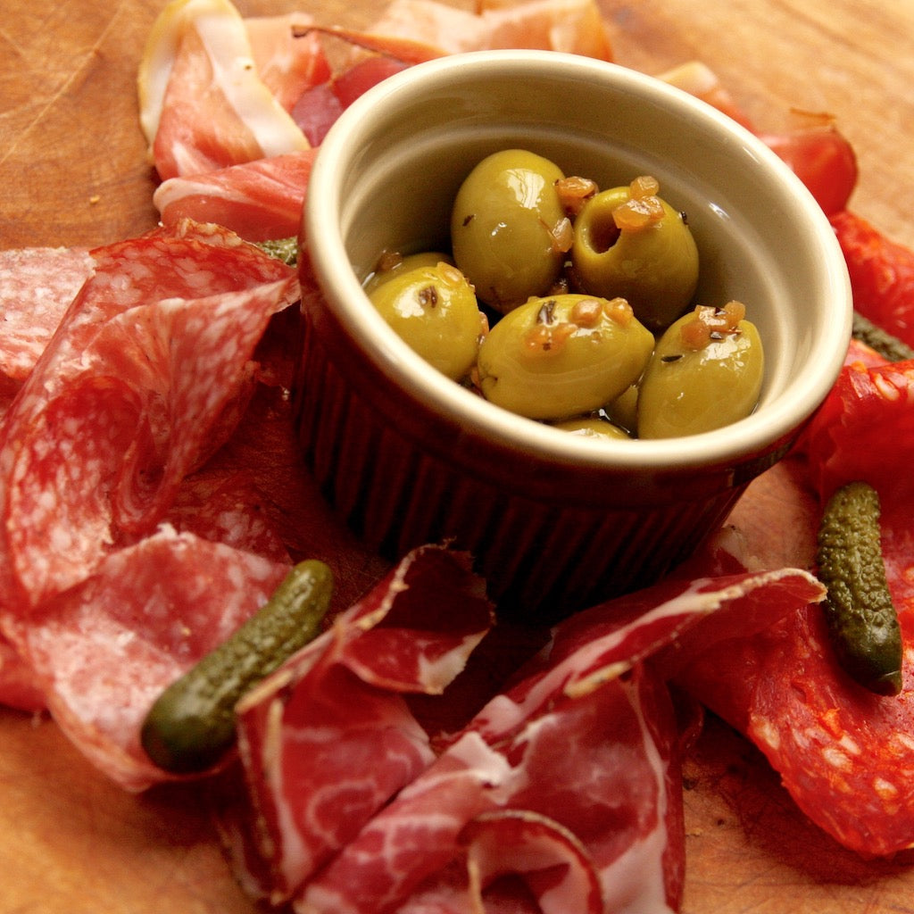 Smoked olives with smoked meats and gherkins on platter