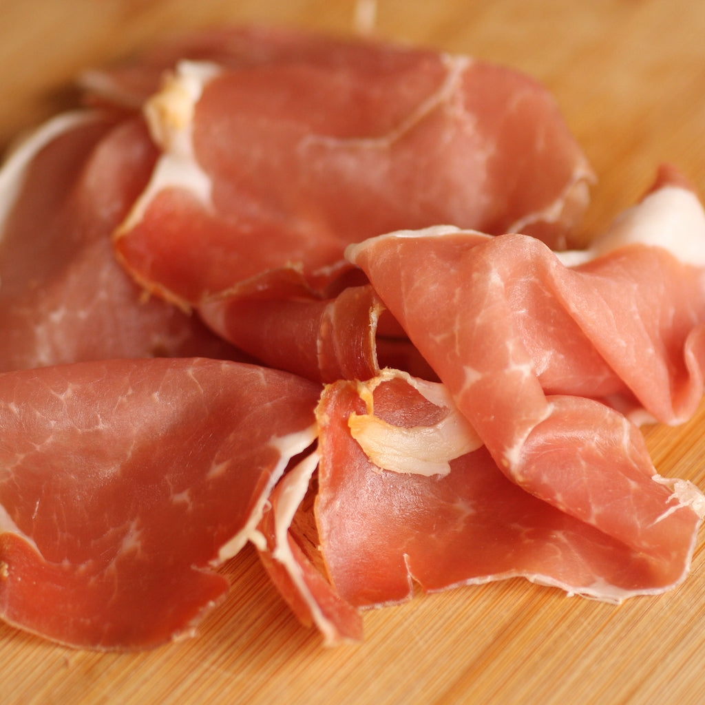 Slices of The Artisan Smokehouse's smoked Prosciutto ham on wooden board