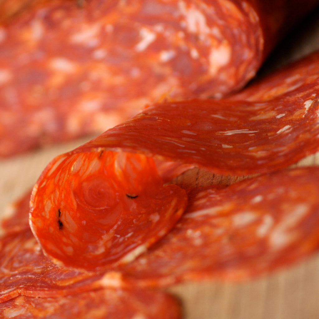 Slices of The Artisan Smokehouse's smoked Spianata Calabra salami on serving board