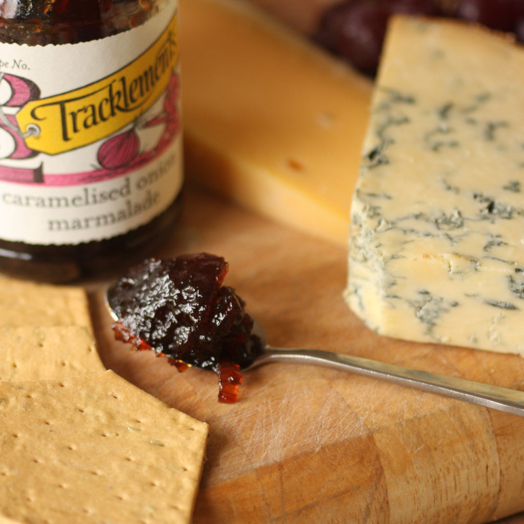 A piece of The Artisan Smokehouse's smoked Stilton on cheese board with crackers and chutney