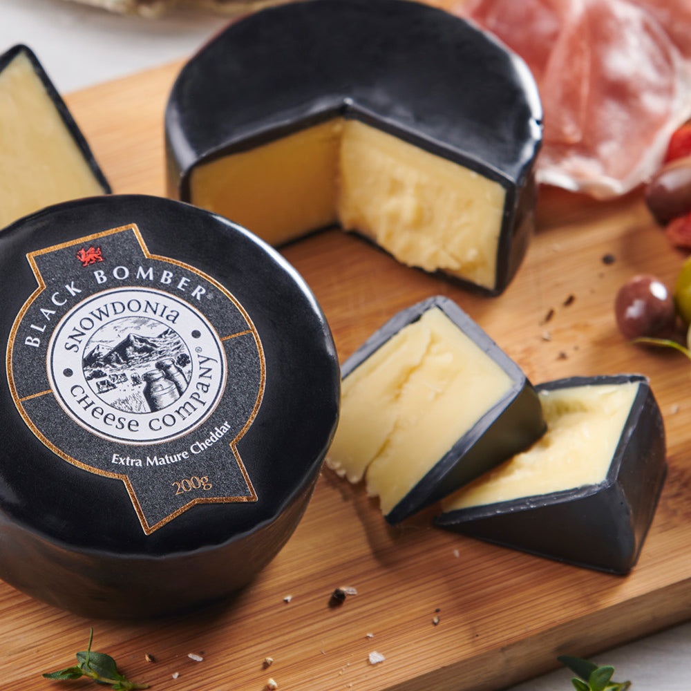 A Snowdonia Black Bomber cheese cut into pieces on cheese board