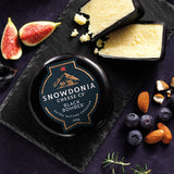 Snowdonia Cheese Co. Black Bomber cheese on a slate board with figs, nuts, and blueberries.