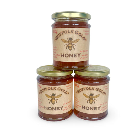 Three jars of Suffolk Gold honey stacked on a white background