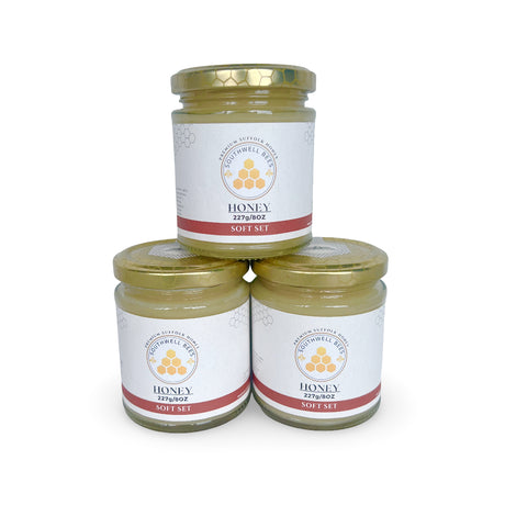 Three jars of soft set honey stacked on a white background with a visible brand label.