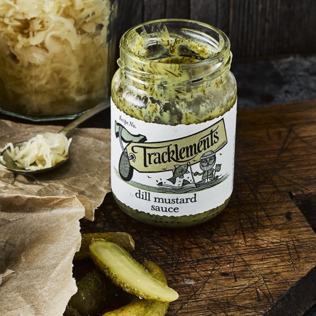 Jar of Tracklements 
dill mustard sauce with a label on a wooden surface with pickles