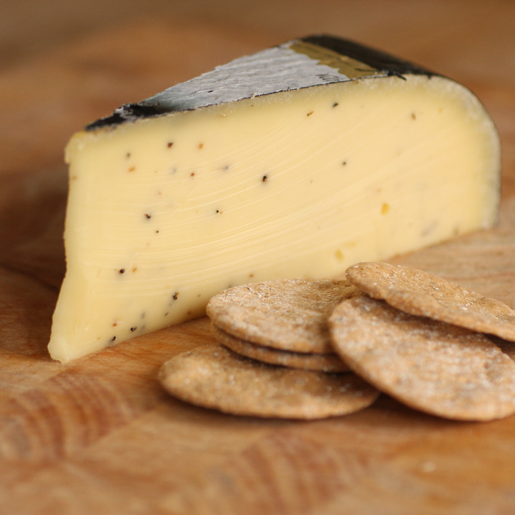 A piece of truffle Gouda on cheese board with crackers