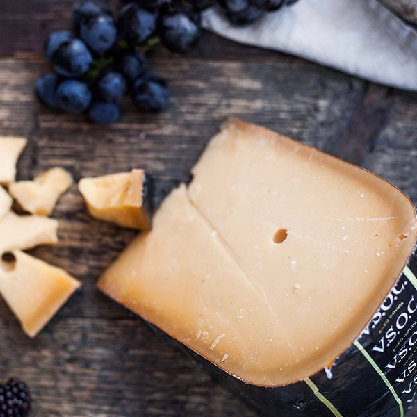 A piece of Weydeland VSOC Gouda on a wooden board with grapes